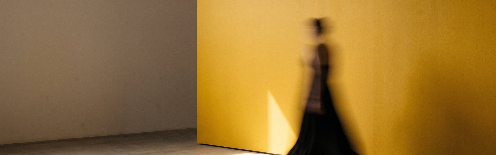 A blurred figure moves past a large chrome-yellow wall, with soft light and shadow on a concrete floor -- Creative Testing Confidence Score.